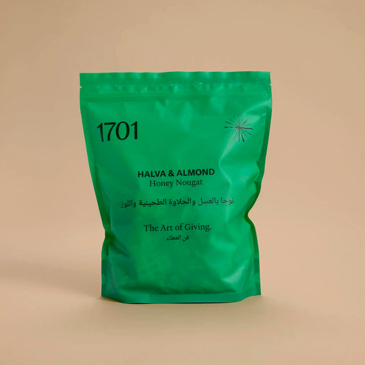 1 kg pouch of Halva & Almond honey nougat, shown in a dark green pouch on a warm background. The pouch is filled with bite-sized pieces of nougat, and the product label is visible on the front of the pouch.